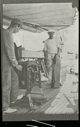 Image of Two men with equipment on deck. 